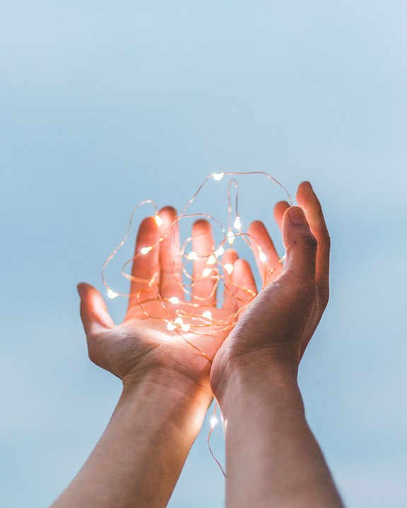 © Diego PH (Unsplash) Hände, die einen leuchtenden Draht halten.
