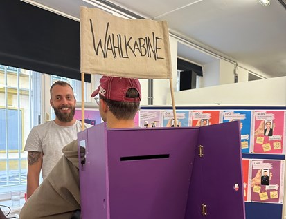 Jugendarbeiter trägt Mobile Wahlbox aus Holz am Rücken