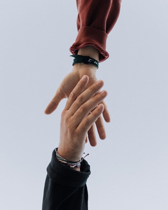 © Unsplash / Austin Kehmeier Zwei Hände, die nacheinander greifen.