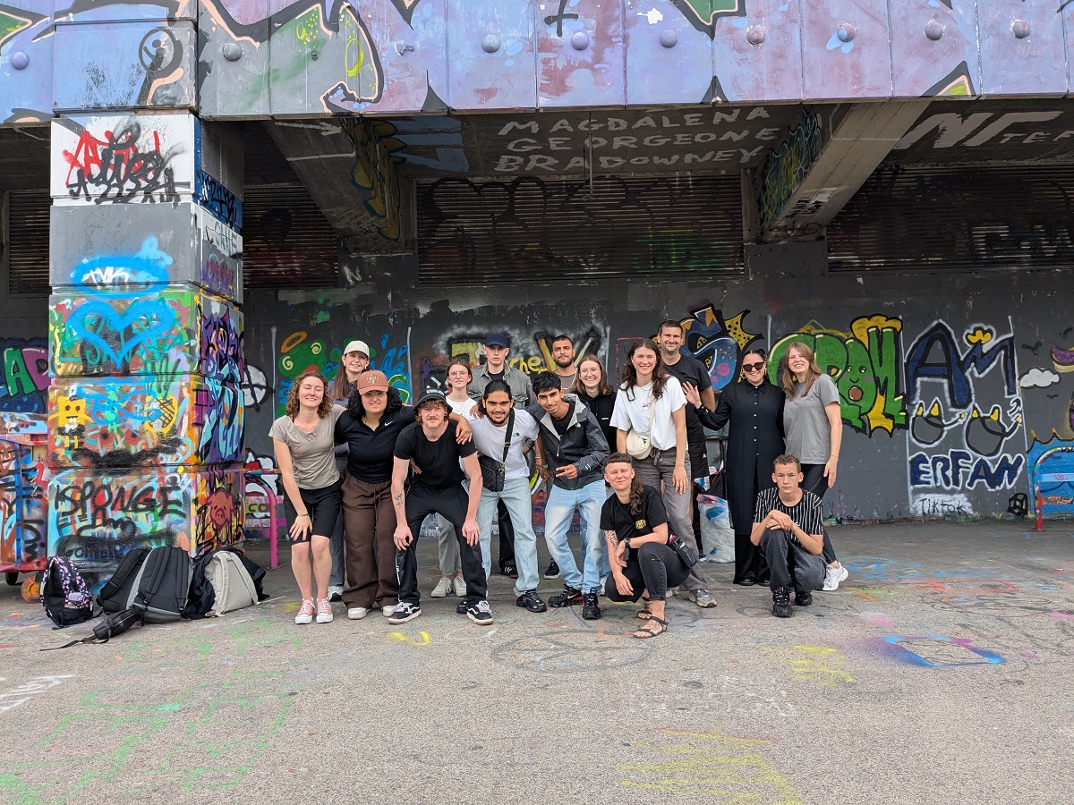 Gruppenfoto von Jugendlichen und Jugendarbeiter:innen vor einer Graffiti-Wand