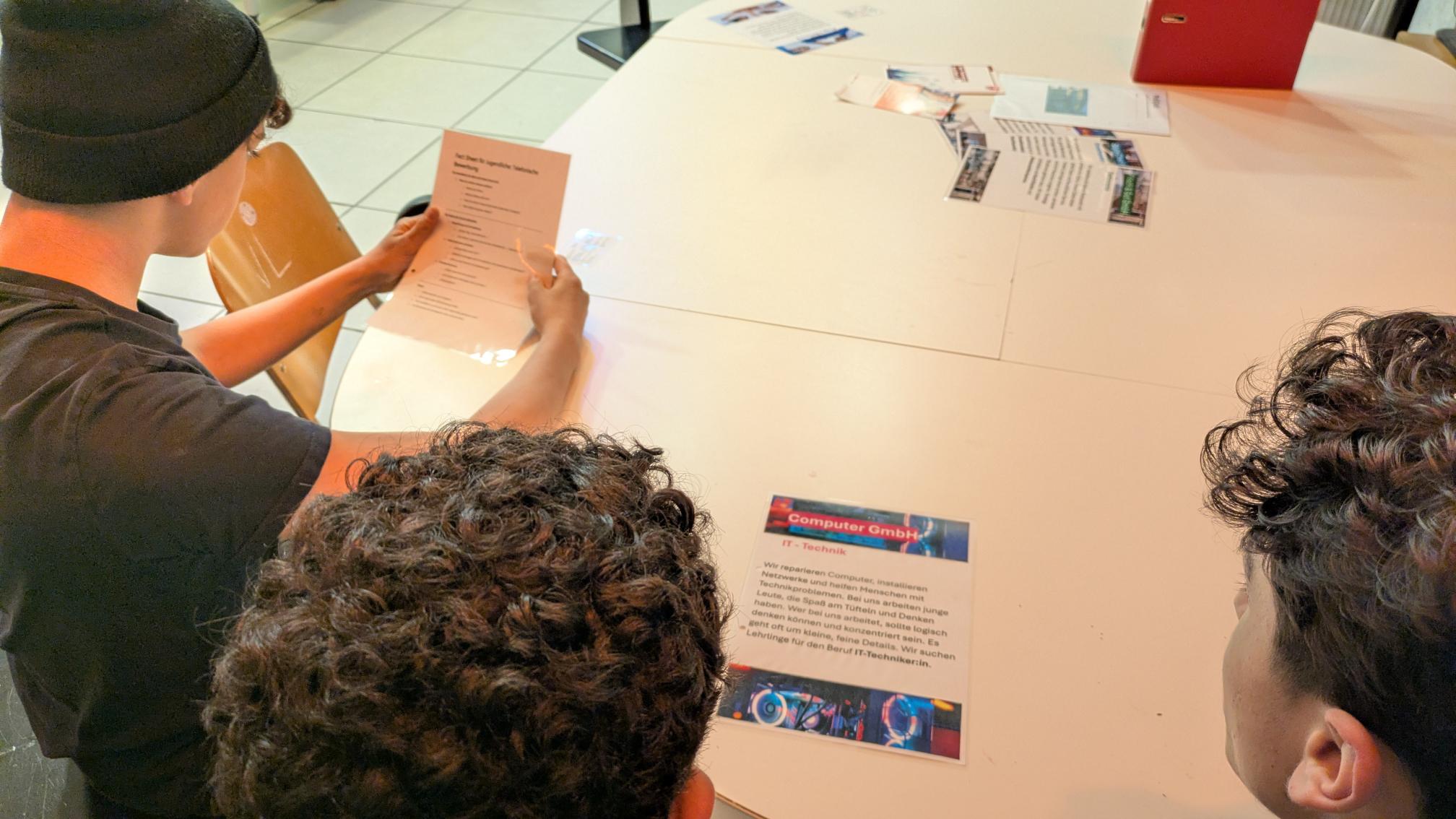 Drei Jugendliche lesen ein Informationsblatt über die IT-Branche