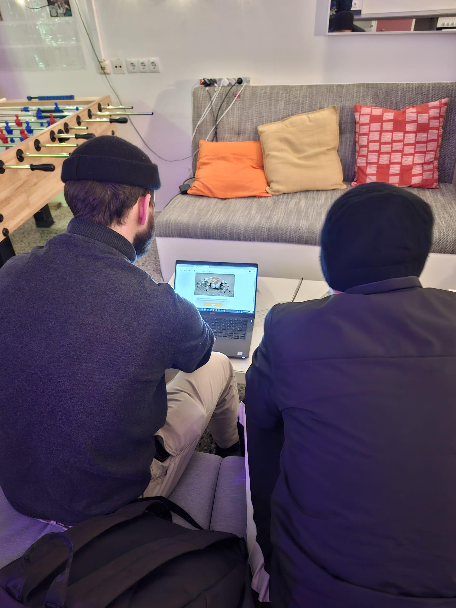 Jugendarbeiter und Jugendlicher von hinten zu sehen, am Laptop