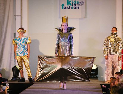 Model mit Krone und goldenem Kleid am Catwalk