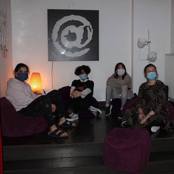 Mädchen sitzen mit Maske am Boden des flash Mädchencafés