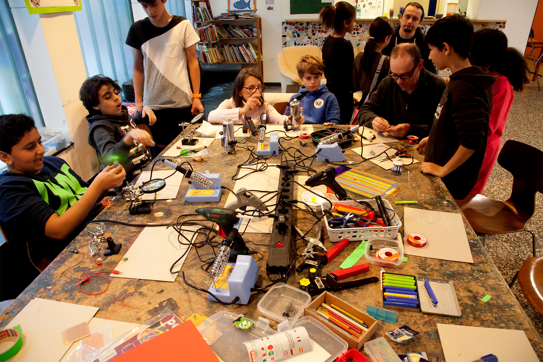Werktisch befüllt mit Kabel, Kids basteln mit Betreuern