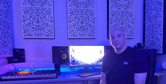 Eine Person sitzt in einem Tonstudio vor einem Bildschirm