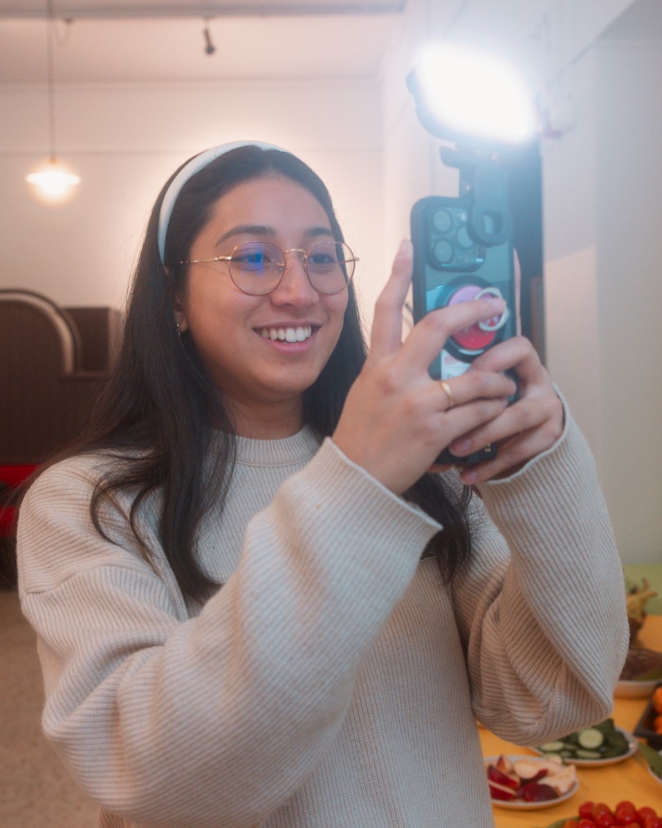 Mädchen* lächelt mit Handy und Licht in der Hand