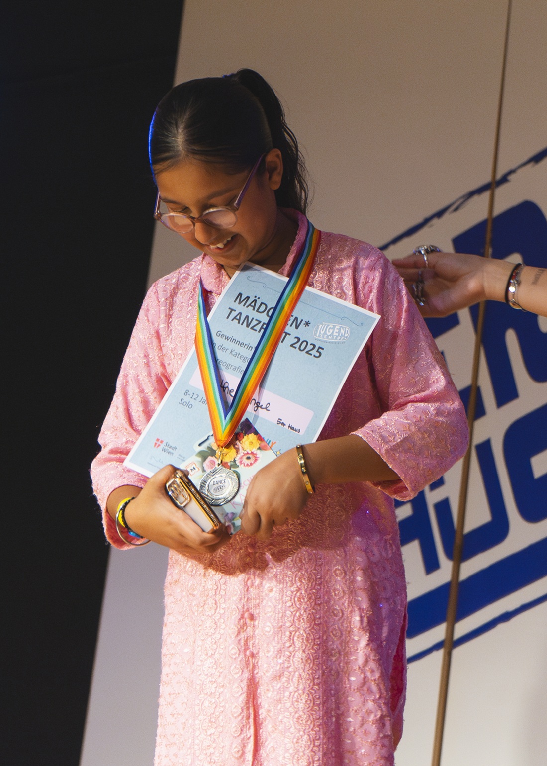 Mädchen* trägt Urkunde und lächelt dabei