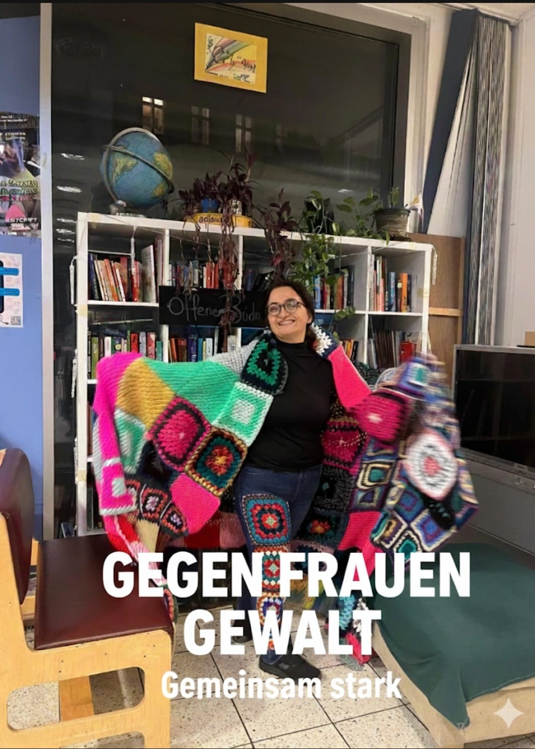Frau trägt Strickdecke über den Schultern, darunter der Schriftzug "Gegen Frauengewalt, Gemeinsam Stark"