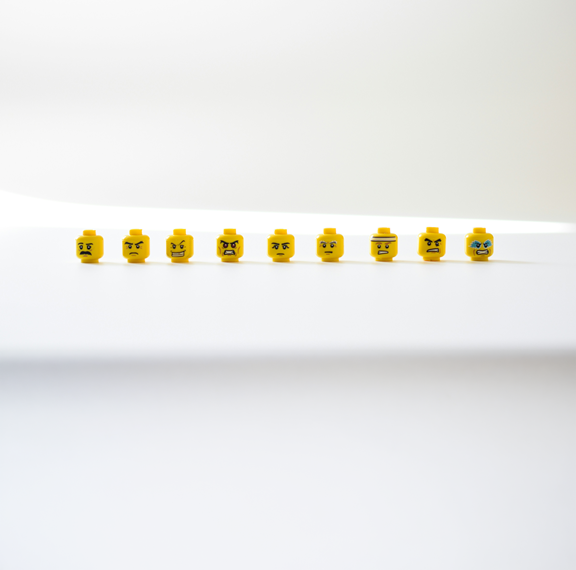 9 Lego-Köpfe mit verschiedenen, wütenden Mimik vor einem weißen, neutralen Hintergrund