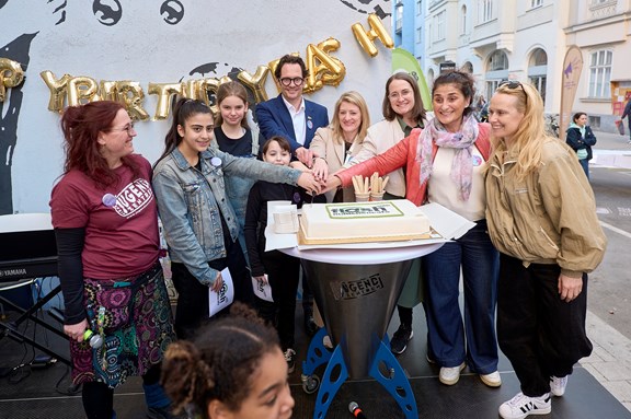 Mädchen* und Erwachsene schneiden auf der Bühne gemeinsam Torte an