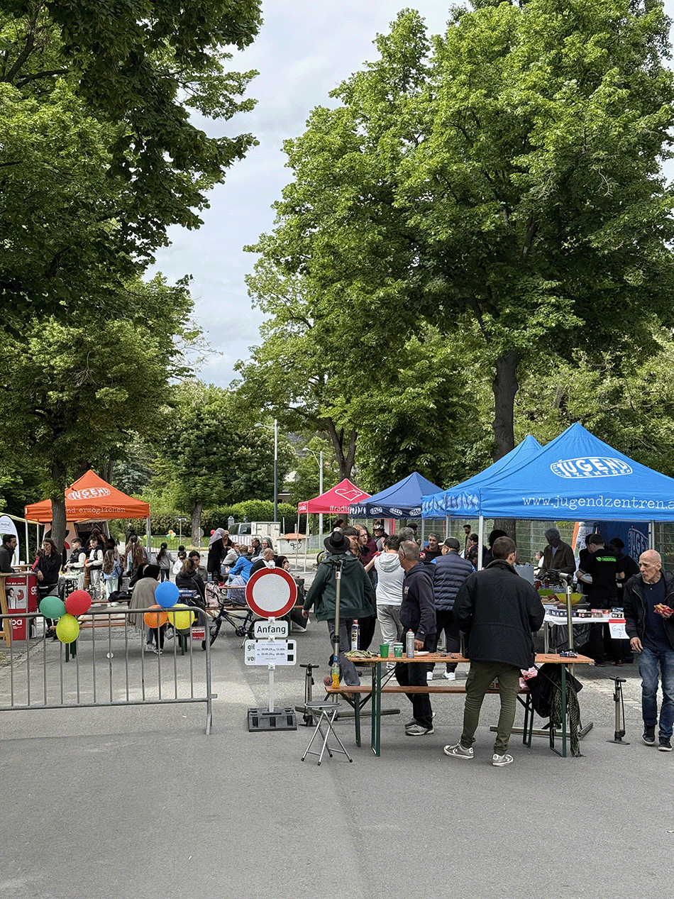 abgesperrte Straße, Zelte, Tische und Bänke mit Personen zu sehen