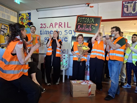 Jugendarbeiter:innen in orangenen Warnwesten applaudieren in der Gruppe