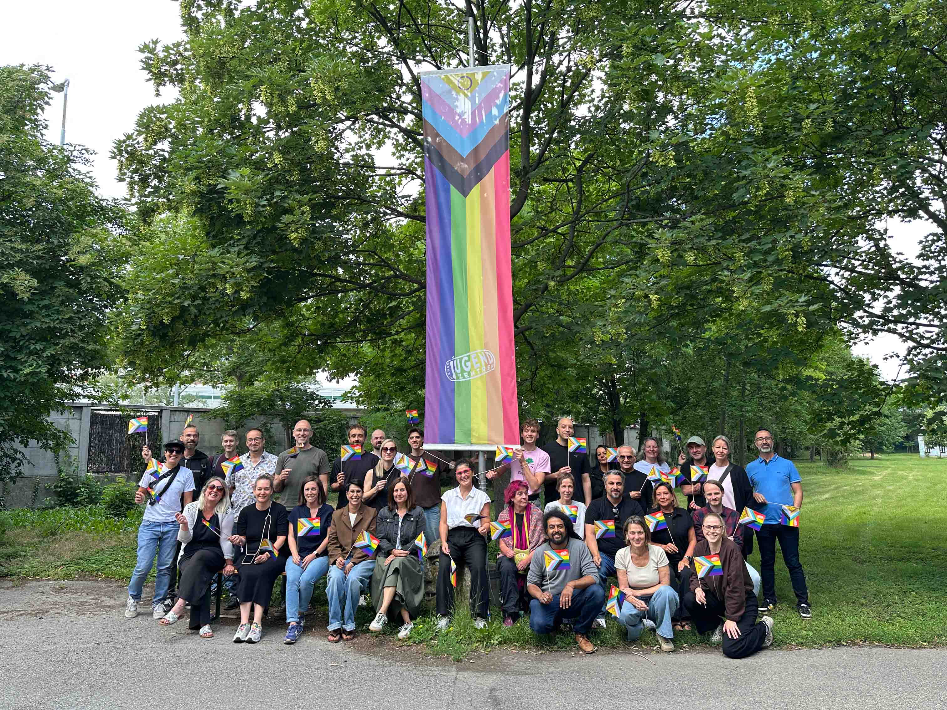 copyright: Verein Wiener Jugendzentren Mitarbeiter:innen hissen die Progress-Pride-Flagge beim Eingang zur zentralen Geschäftsstelle des Vereins Wiener Jugendzentren.