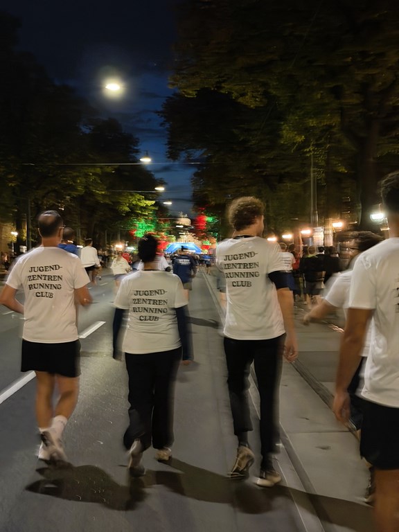 Kolleg:innen mit VJZ-Laufshirt von hinten zu sehen, Slogan am Shirt: Jugendzentren-Running Club