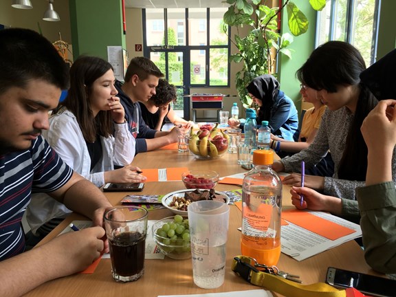 Jugendliche sitzen an einem Tisch und erledigen gemeinsam Aufgaben