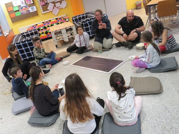 Kinder sitzen mit Jugendarbeiter_innen im Kreis. 