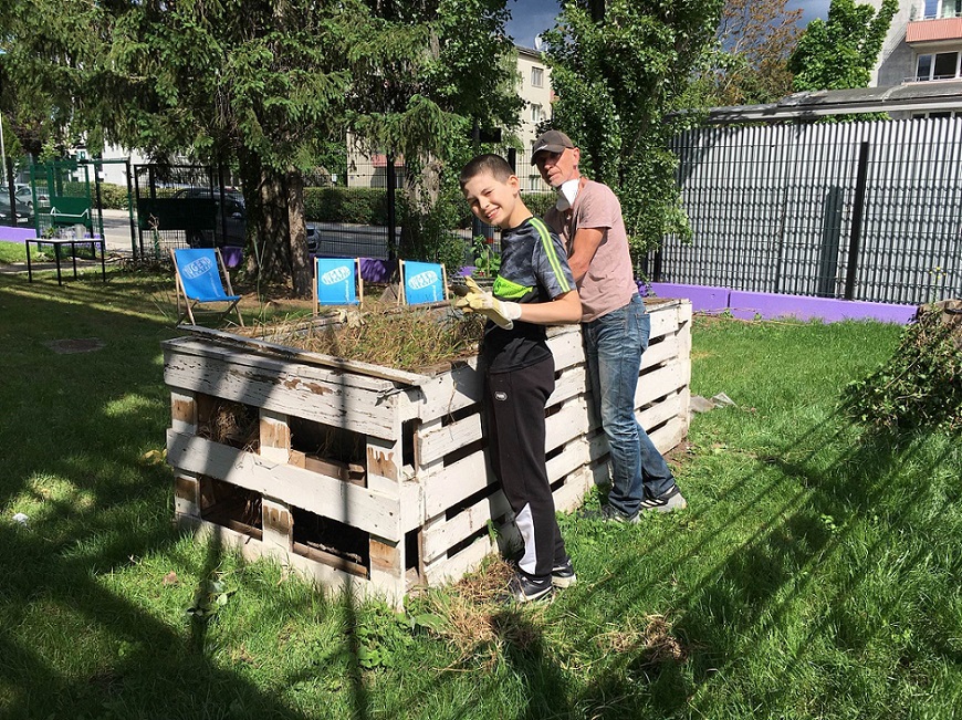 Kind und Betreuer jäten beim Hochbeet beim Jugendzentrum Meidling